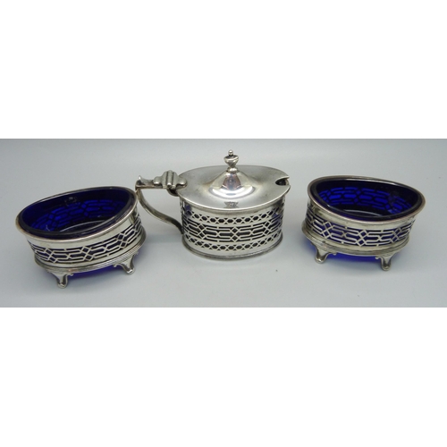 864 - A silver three piece cruet set with blue glass liners, Chester 1916; a pair of salts and mustard, 14... 