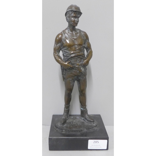 285 - A bronze figure of a miner, on black marble socle