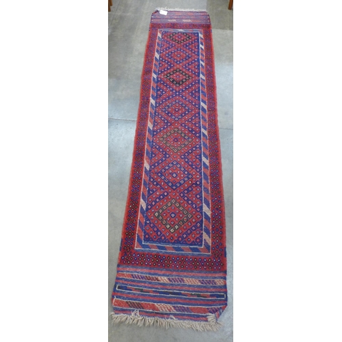 90 - An eastern red ground runner rug, 263 x 57cms