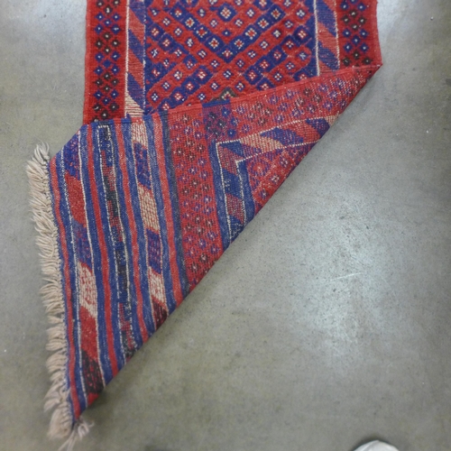 90 - An eastern red ground runner rug, 263 x 57cms