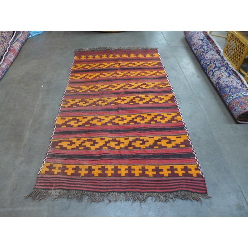 93A - A red, orange and black rug, 252 x 145cms