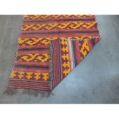 93A - A red, orange and black rug, 252 x 145cms