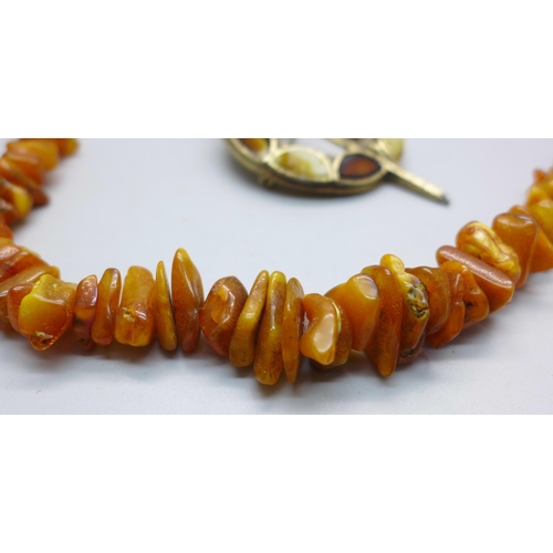 1100 - A Baltic amber necklace and a Scottish kilt pin style brooch