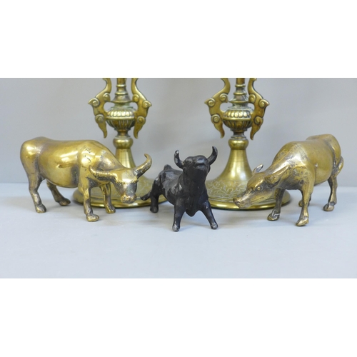 617 - A pair of Indian brass candlesticks, two brass oxen and a metal model of a bull