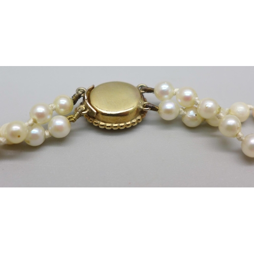 888 - A graduated double string pearl necklace, the yellow metal clasp set with a pink stone, tests as ame... 