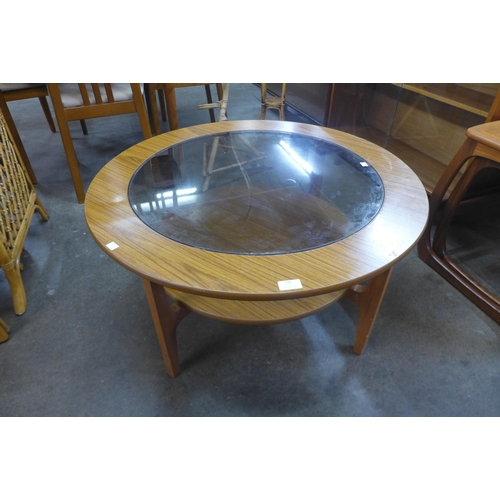 176 - A teak and glass topped circular coffee table