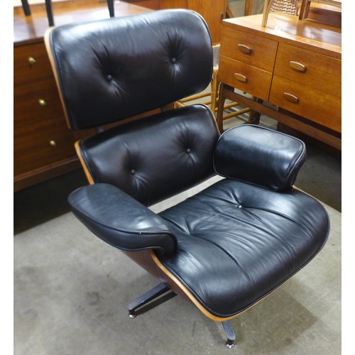 154 - A Charles & Ray Eames style simulated rosewood and black leather revolving lounge chair and ottoman