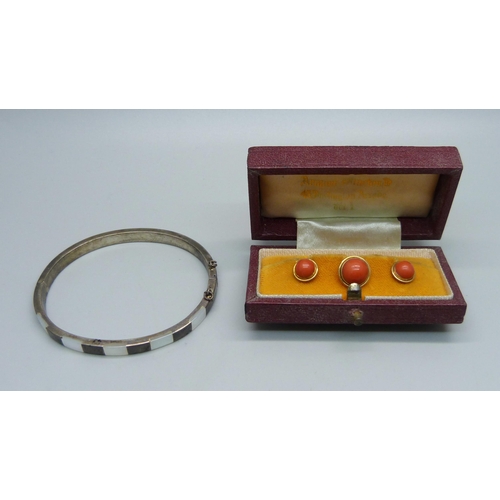 1010 - A silver and mother of pearl bangle and a cased set of yellow metal and cabochon coral shirt studs