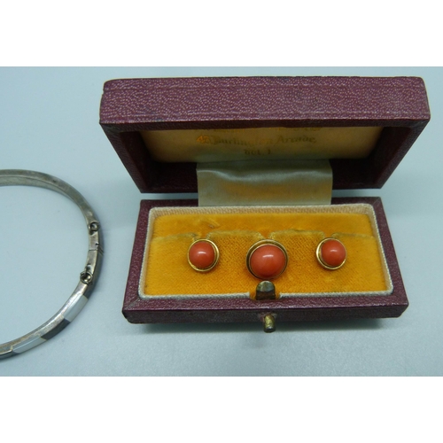 1010 - A silver and mother of pearl bangle and a cased set of yellow metal and cabochon coral shirt studs