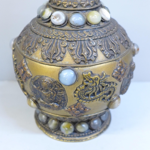 610 - An embossed Tibetan brass vase set with thirty-nine cabochon stones, 24cm