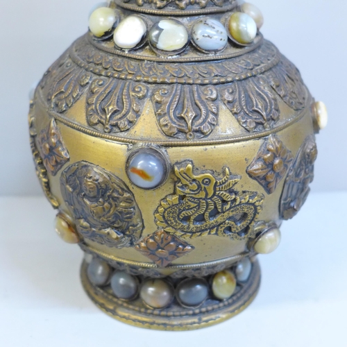 610 - An embossed Tibetan brass vase set with thirty-nine cabochon stones, 24cm