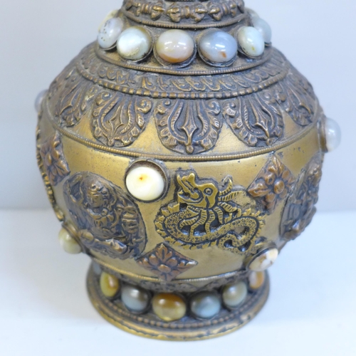 610 - An embossed Tibetan brass vase set with thirty-nine cabochon stones, 24cm