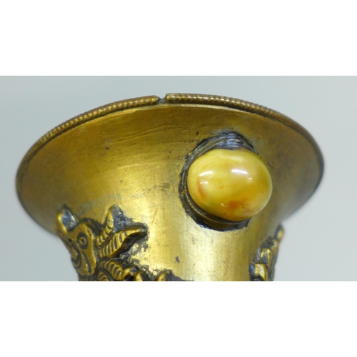 610 - An embossed Tibetan brass vase set with thirty-nine cabochon stones, 24cm