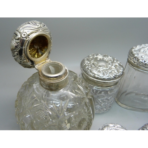 837 - Ten silver topped glass bottles including a globular glass scent bottle, lid a/f