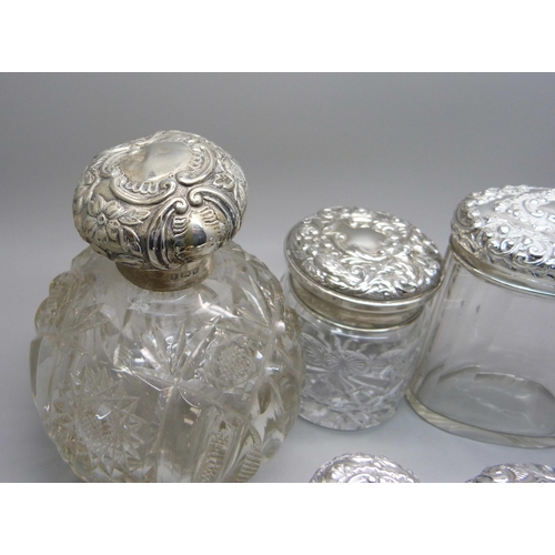 837 - Ten silver topped glass bottles including a globular glass scent bottle, lid a/f