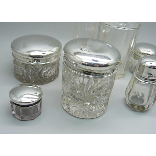 879 - Nine silver topped glass bottles and jars