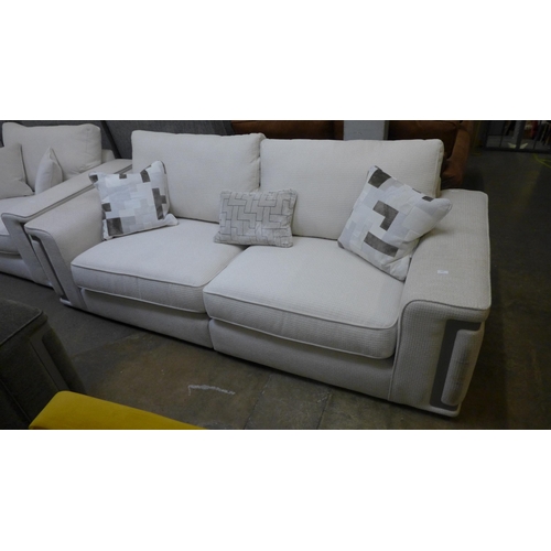 1437 - A cream four seater sofa with steel trim -handling marks