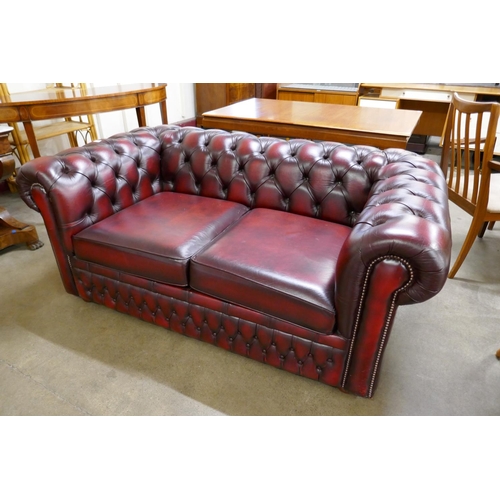 67 - An oxblood red leather Chesterfield settee/bed