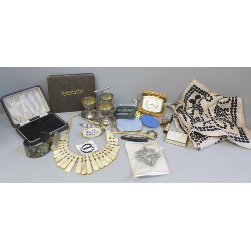 773 - A collection of vintage items including a travel clock, egg cups, a buckle, a book containing hand w... 