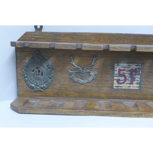 824 - An oak pipe rack, 51st Highlanders with five applied badges