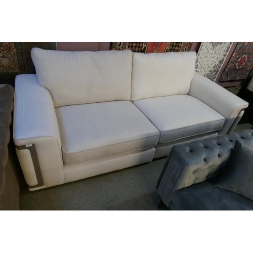 1541 - A cream upholstered three seater sofa with steel trim - differing fabric batches on each section