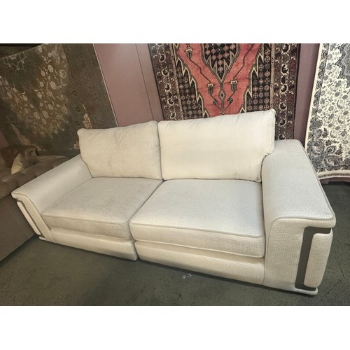 1541 - A cream upholstered three seater sofa with steel trim - differing fabric batches on each section