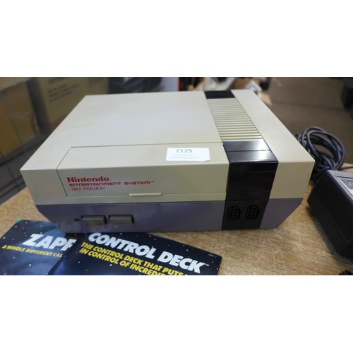 2125 - A Nintendo Entertainment System (NES) console with four game cartridges including Super Mario/Duck h... 