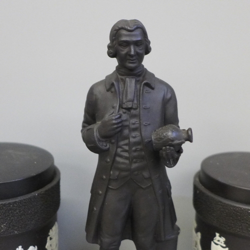 636 - A Wedgwood Josiah Wedgwood figure and a pair of Wedgwood black basalt tobacco jars with match strike... 