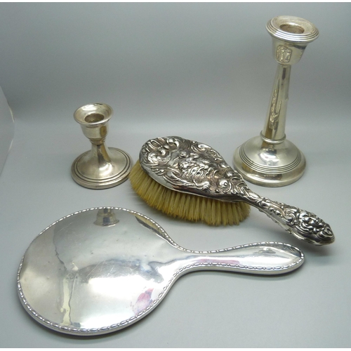 902 - Two silver candlesticks, a silver backed mirror and a silver brush