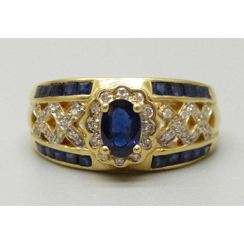 1083 - An 18ct gold cluster ring set with a central oval sapphire measuring approximately 0.53ct, twelve di... 