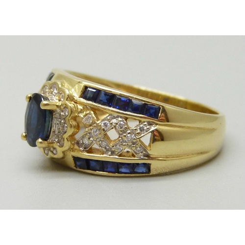 1083 - An 18ct gold cluster ring set with a central oval sapphire measuring approximately 0.53ct, twelve di... 