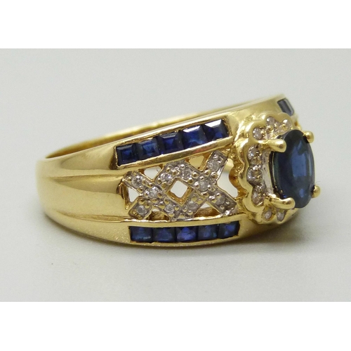 1083 - An 18ct gold cluster ring set with a central oval sapphire measuring approximately 0.53ct, twelve di... 