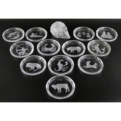 833 - A set of twelve astrological star sign wine coasters by Val St Lambert, and a glass hedgehog, signed