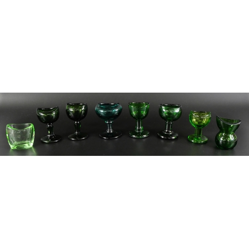 836 - Eight green glass eye baths, some hand blown