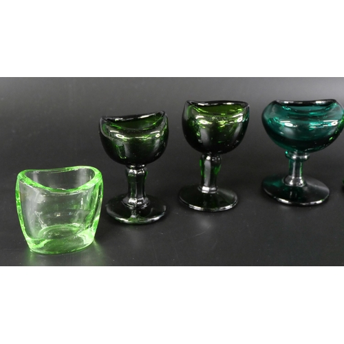 836 - Eight green glass eye baths, some hand blown