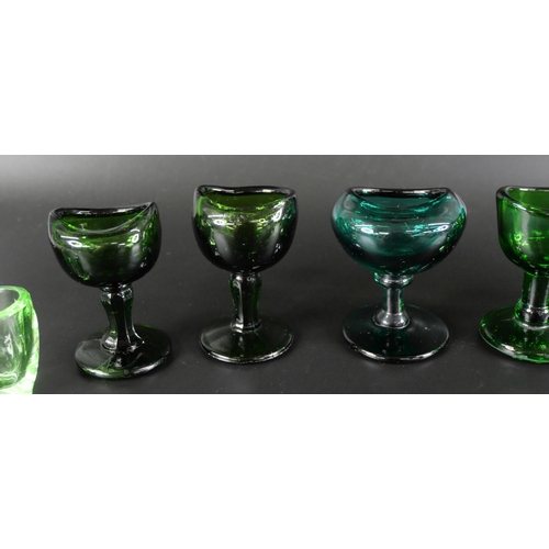 836 - Eight green glass eye baths, some hand blown