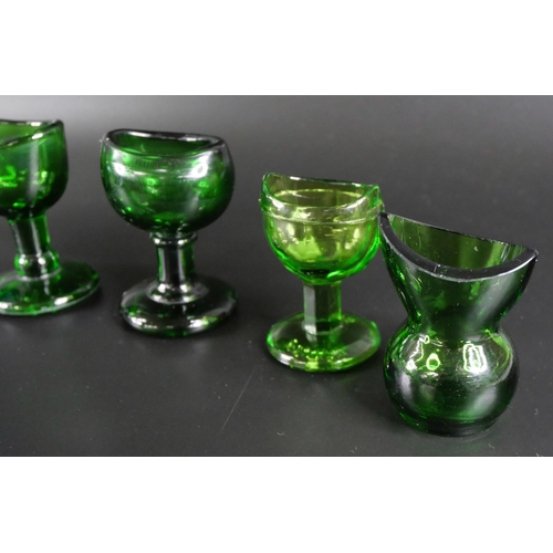 836 - Eight green glass eye baths, some hand blown