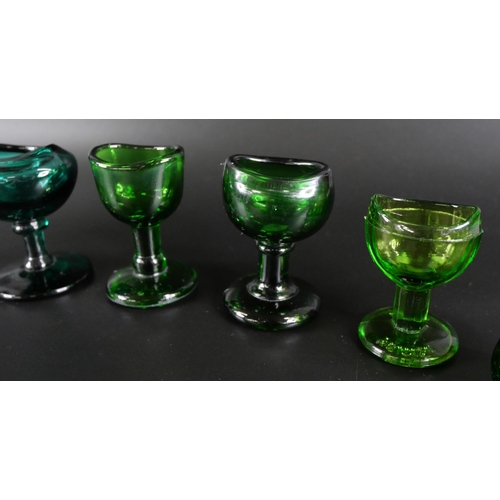 836 - Eight green glass eye baths, some hand blown