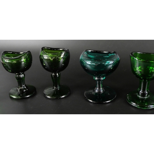 836 - Eight green glass eye baths, some hand blown