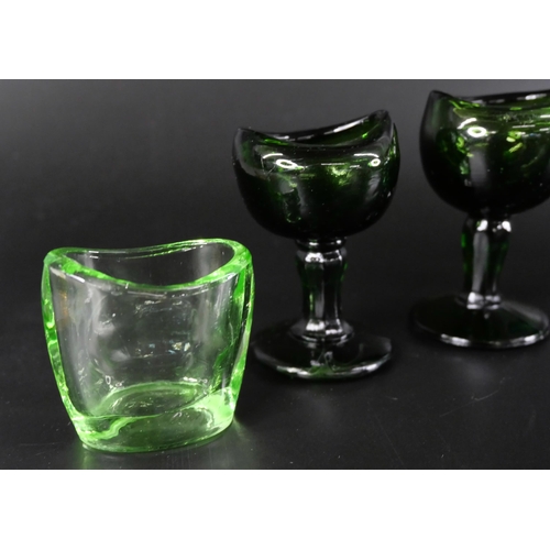 836 - Eight green glass eye baths, some hand blown