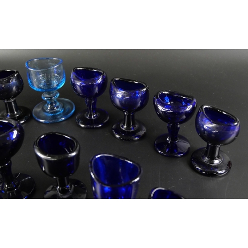 838 - Eighteen blue glass eye baths, some hand blown