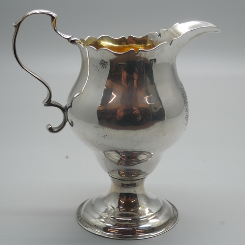 894 - A Georgian silver cream jug with gilt interior, London 1776, with crest, 73g