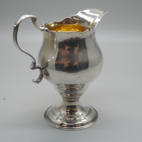 894 - A Georgian silver cream jug with gilt interior, London 1776, with crest, 73g