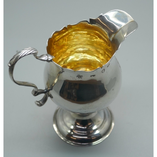 894 - A Georgian silver cream jug with gilt interior, London 1776, with crest, 73g