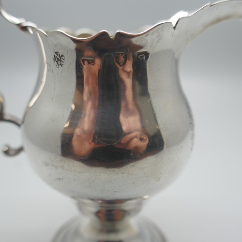 894 - A Georgian silver cream jug with gilt interior, London 1776, with crest, 73g