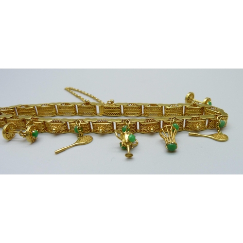 1107 - A yellow metal and jade set bracelet with badminton related charms, marked 14k, 16.5g