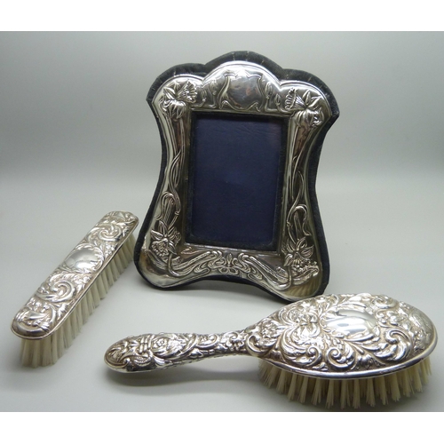 882 - Two silver backed brushes and a silver photograph frame