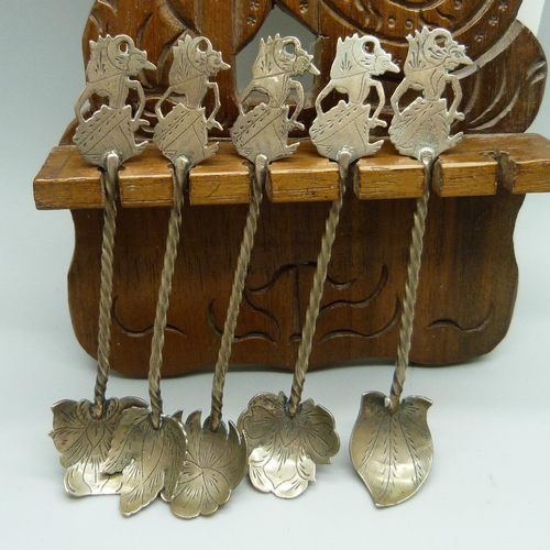 941 - A set of five Eastern .800 silver spoons in a carved wooden display rack