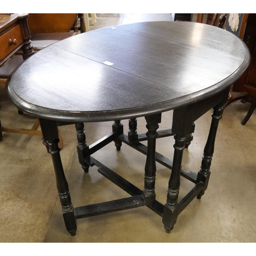 185 - A black oak drop leaf table and a Delft rack