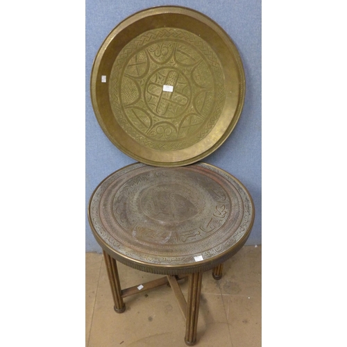 254 - An Islamic copper topped occasional table and a brass charger